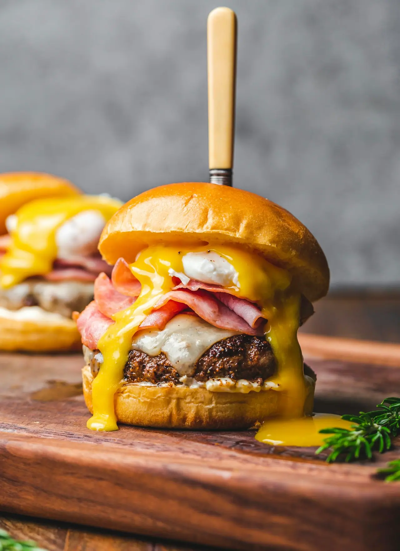 Hambúrguer com ovo, presunto e queijo escorrendo, em close