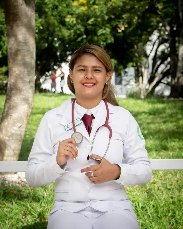 Dra. Júlia Teixeira, fisioterapeuta, de jaleco e estetoscópio, ao ar livre