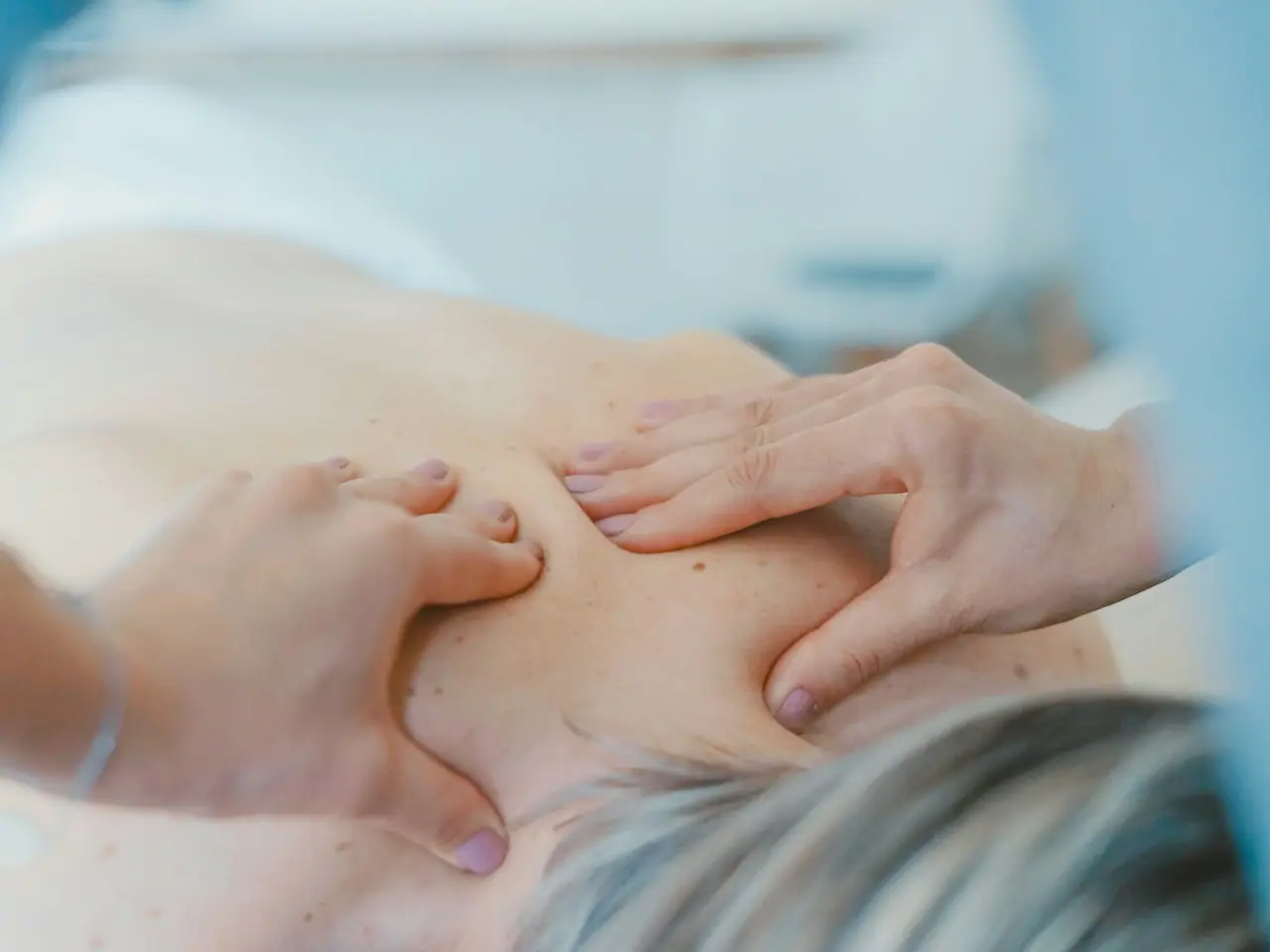 Mãos de fisioterapeuta fazendo terapia manual nas costas de uma paciente